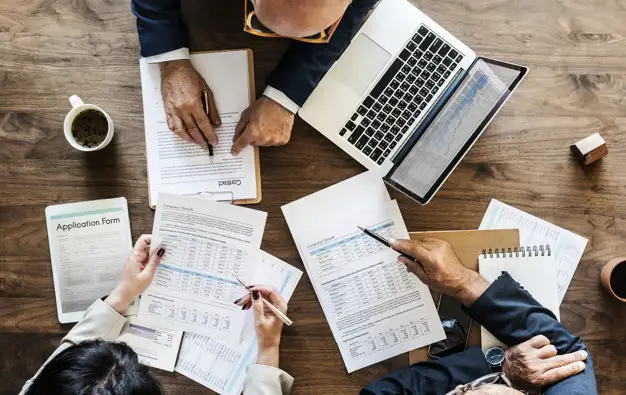 Equipe analisando documentos e contratos sobre a mesa de reunião